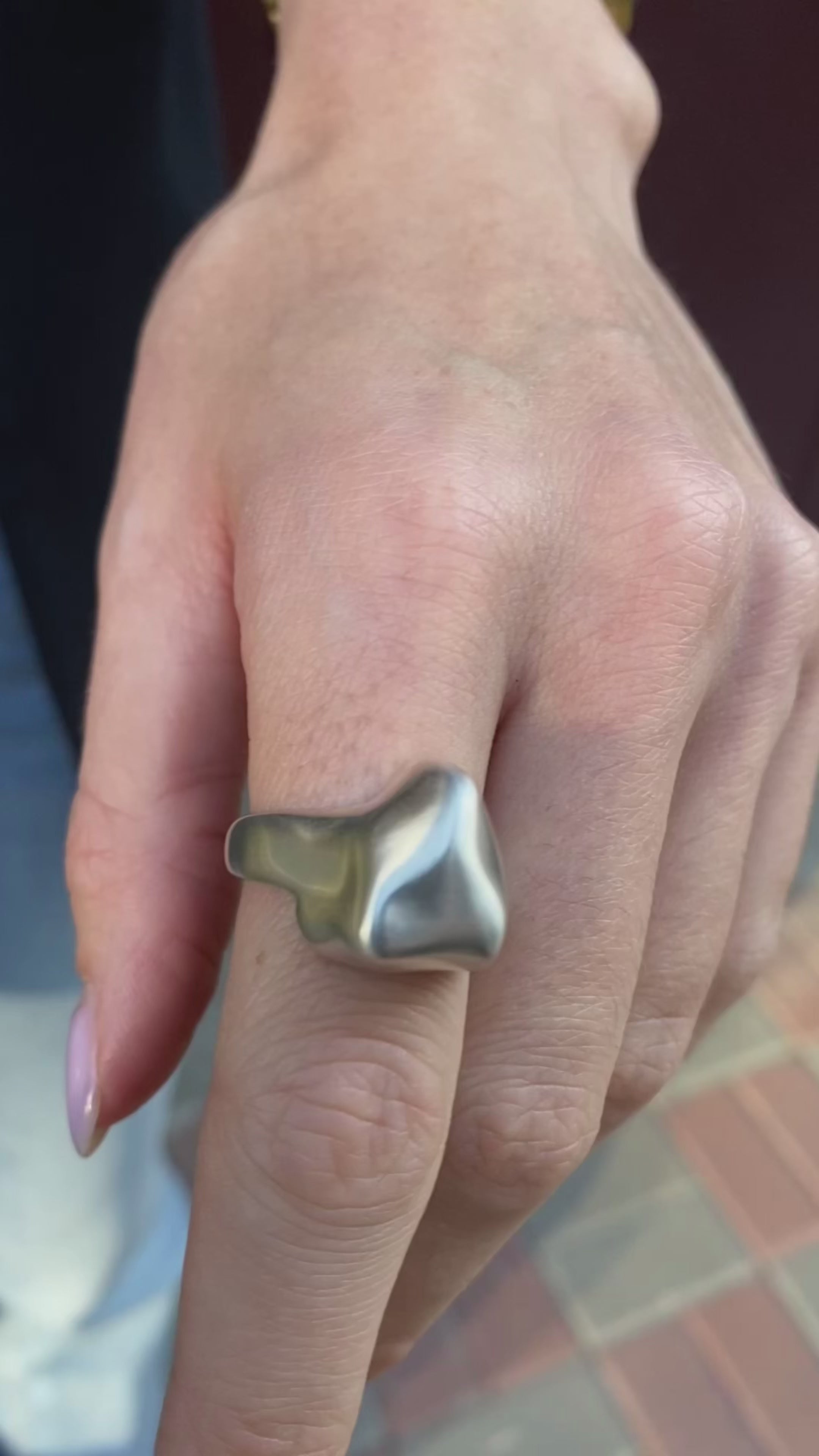 Close-up view of a chunky triangle ring in polished silver.